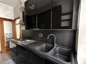 A modern kitchen with a gas stove, two stainless steel sinks, and black cabinetry. - Jireh vacation home - Two Bedroom Apartment, Sleeps 5 (Rome)
