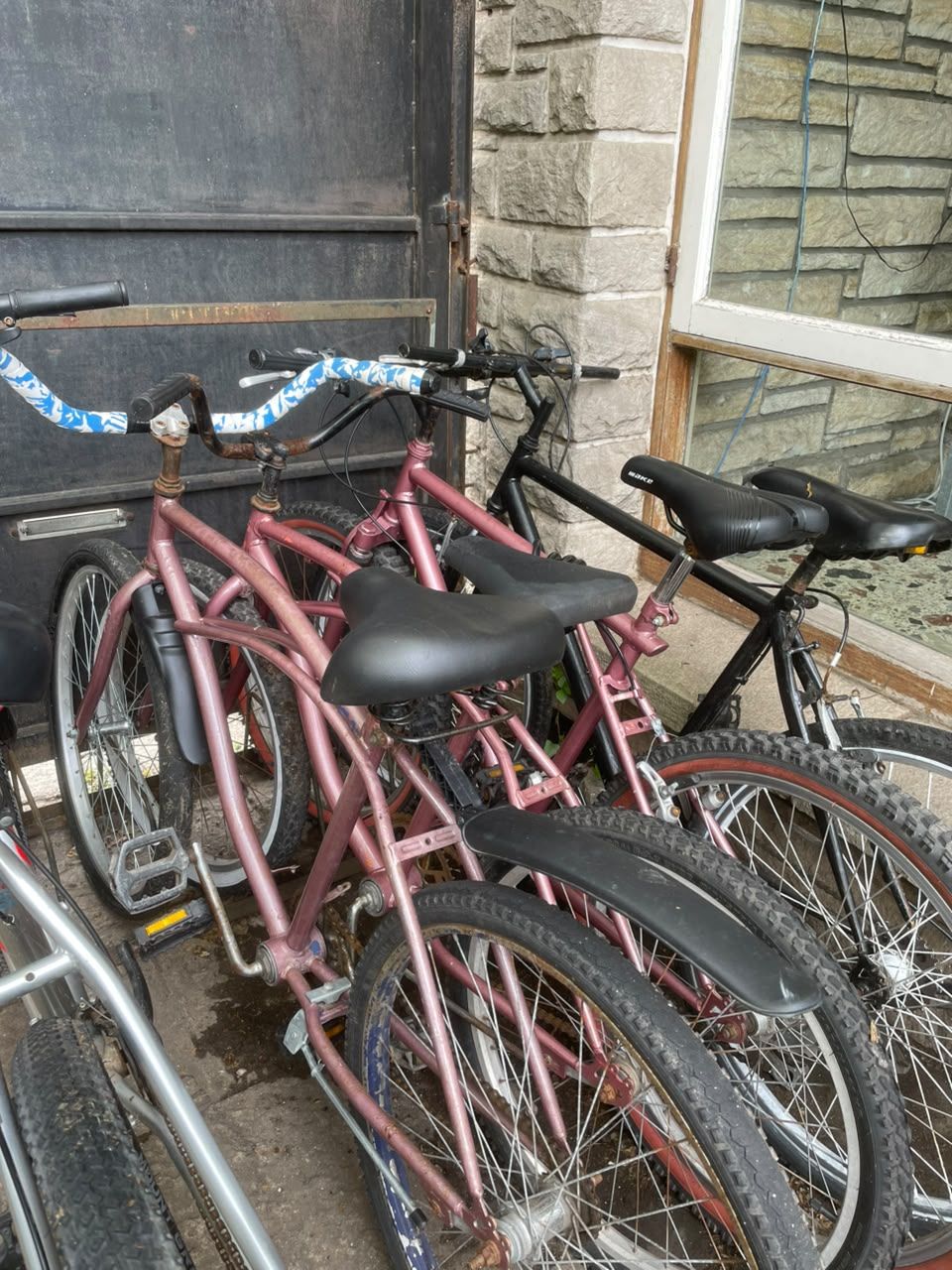 Una bicicleta apoyada en una pared de piedra con una puerta al fondo.