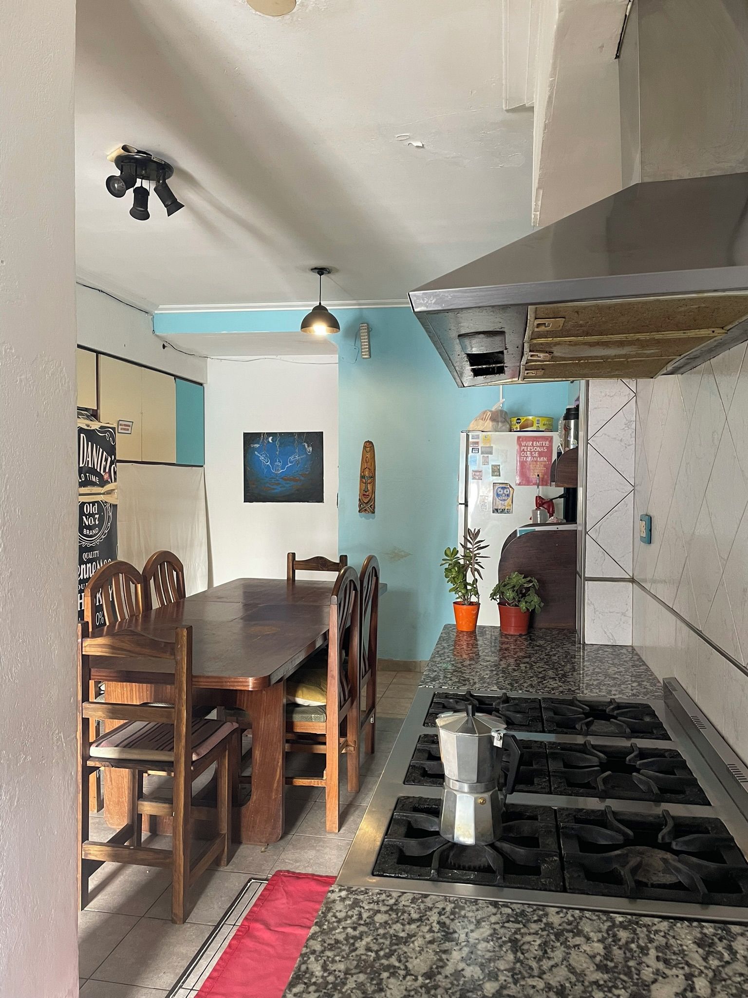 Cocina compacta con comedor, estufa a gas y refrigerador.