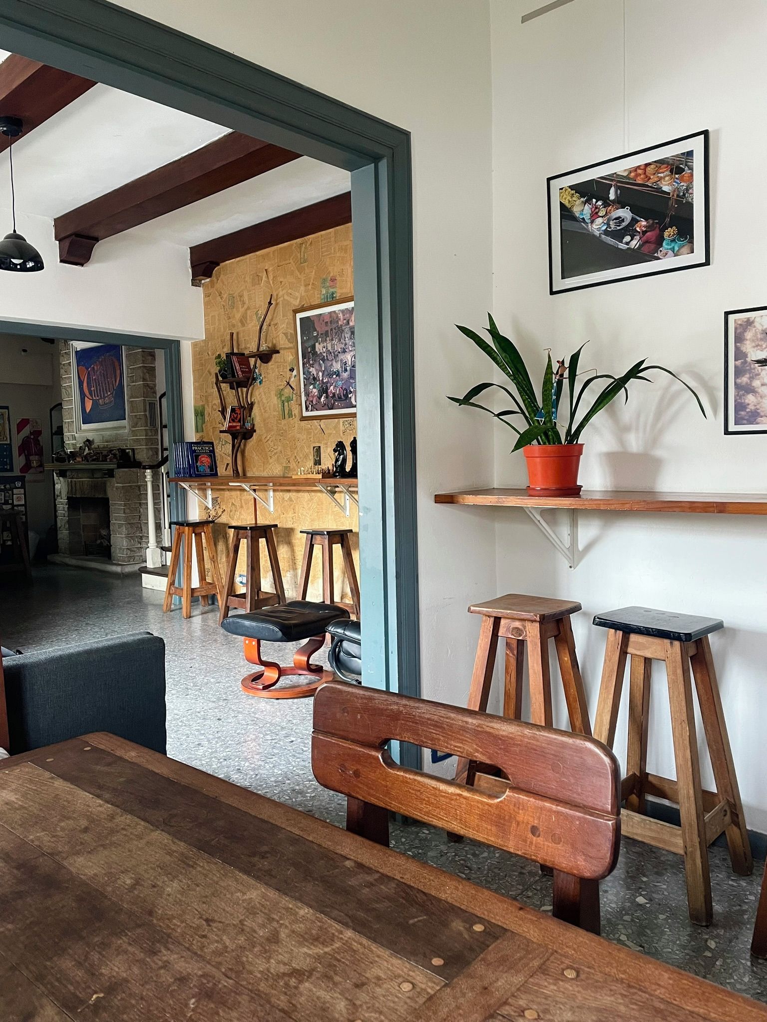 A dining area with a wooden bench, stools, and a potted plant on a shelf.