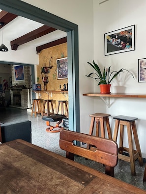 A dining area with a wooden bench, stools, and a potted plant on a shelf. - Zeppelin Art Hostel (Mar del Plata)