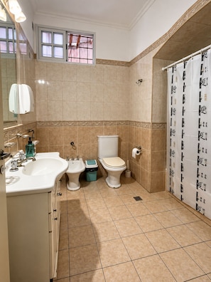 A bathroom with a sink, bidet, toilet, and a shower curtain with text. - Zeppelin Art Hostel (Mar del Plata)