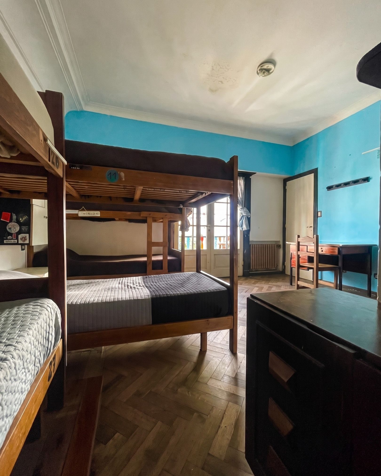 A dormitory room with bunk beds, a desk, and a chair.