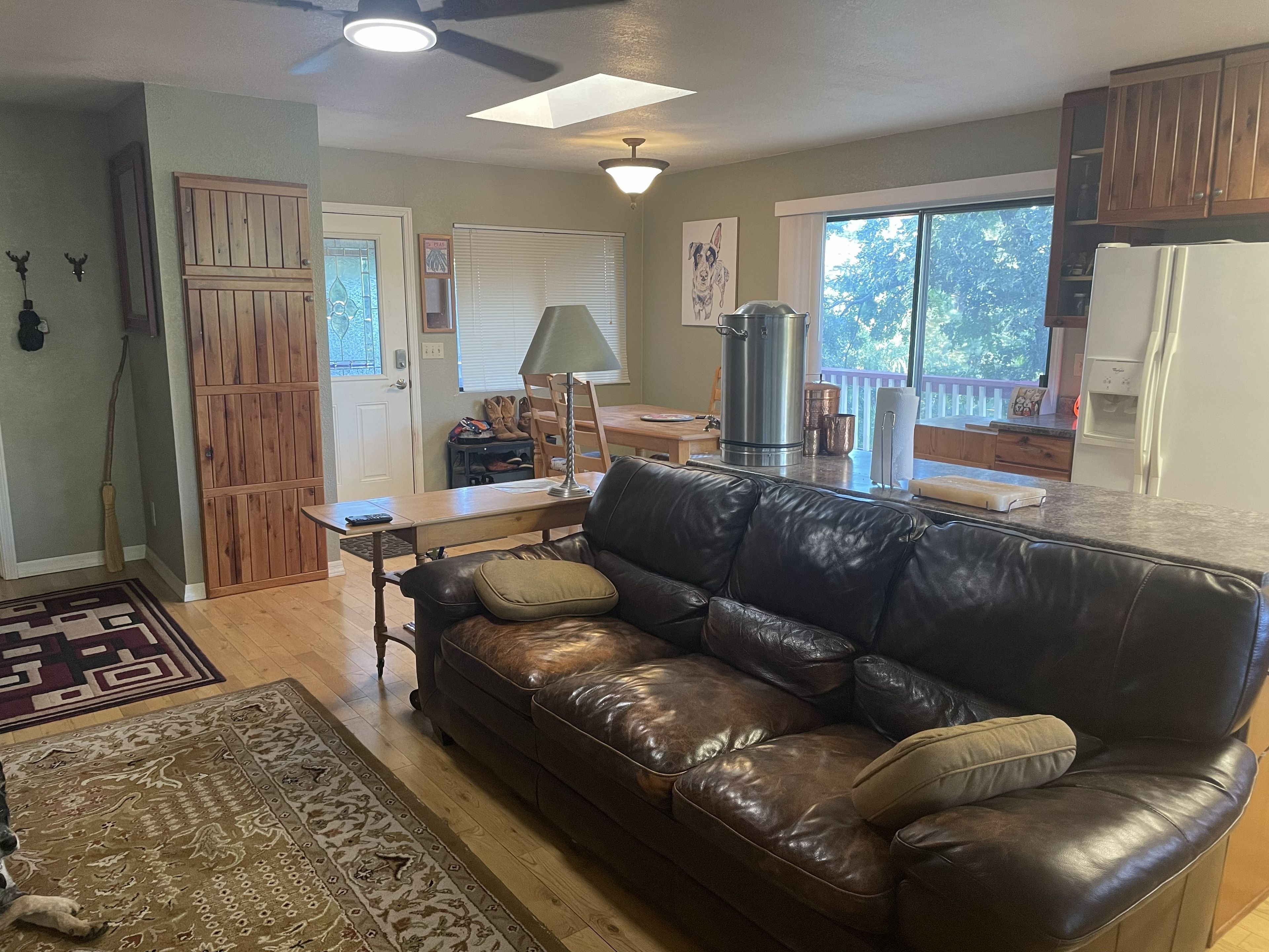 A living room with a leather couch, a coffee table, and a dining area with a table and chairs.