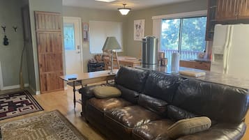 A living room with a leather couch, a coffee table, and a dining area with a table and chairs.