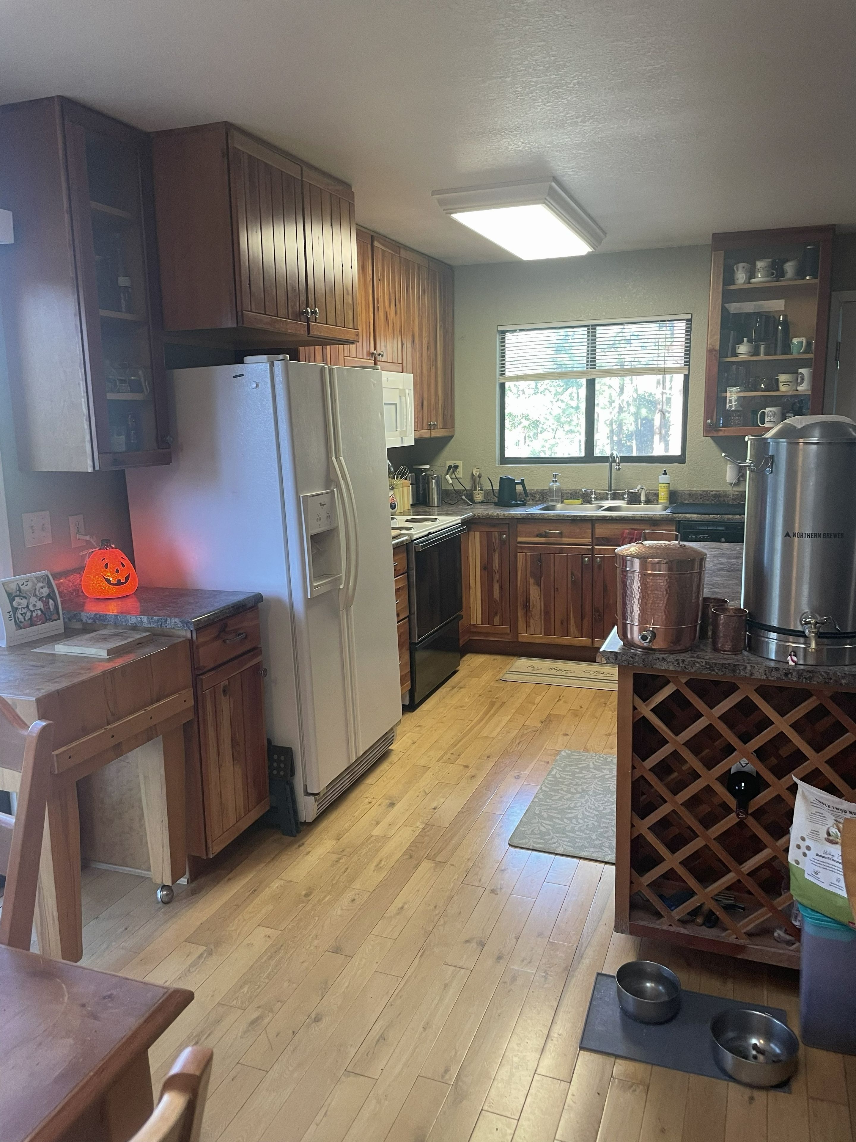 Une cuisine avec des meubles de rangement en bois, un réfrigérateur, une cuisinière et un évier.