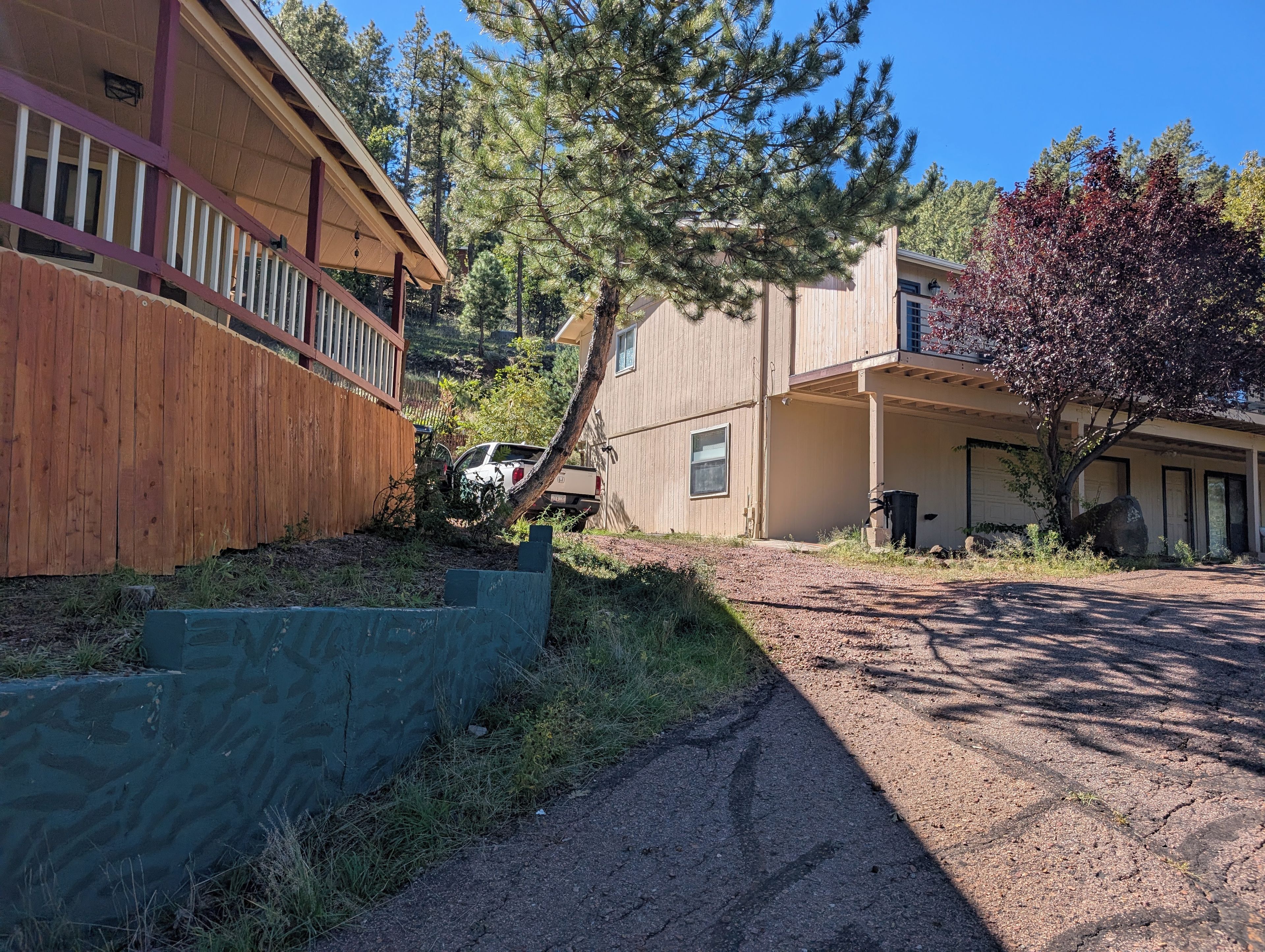 A residential area with a wooden fence, a driveway, and a tree.