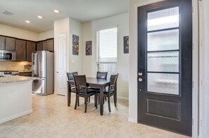 A kitchen with a refrigerator, microwave, and dining table with chairs. - Elegant 3BR Townhome Private Yard & 2-Car Garage (Richmond)