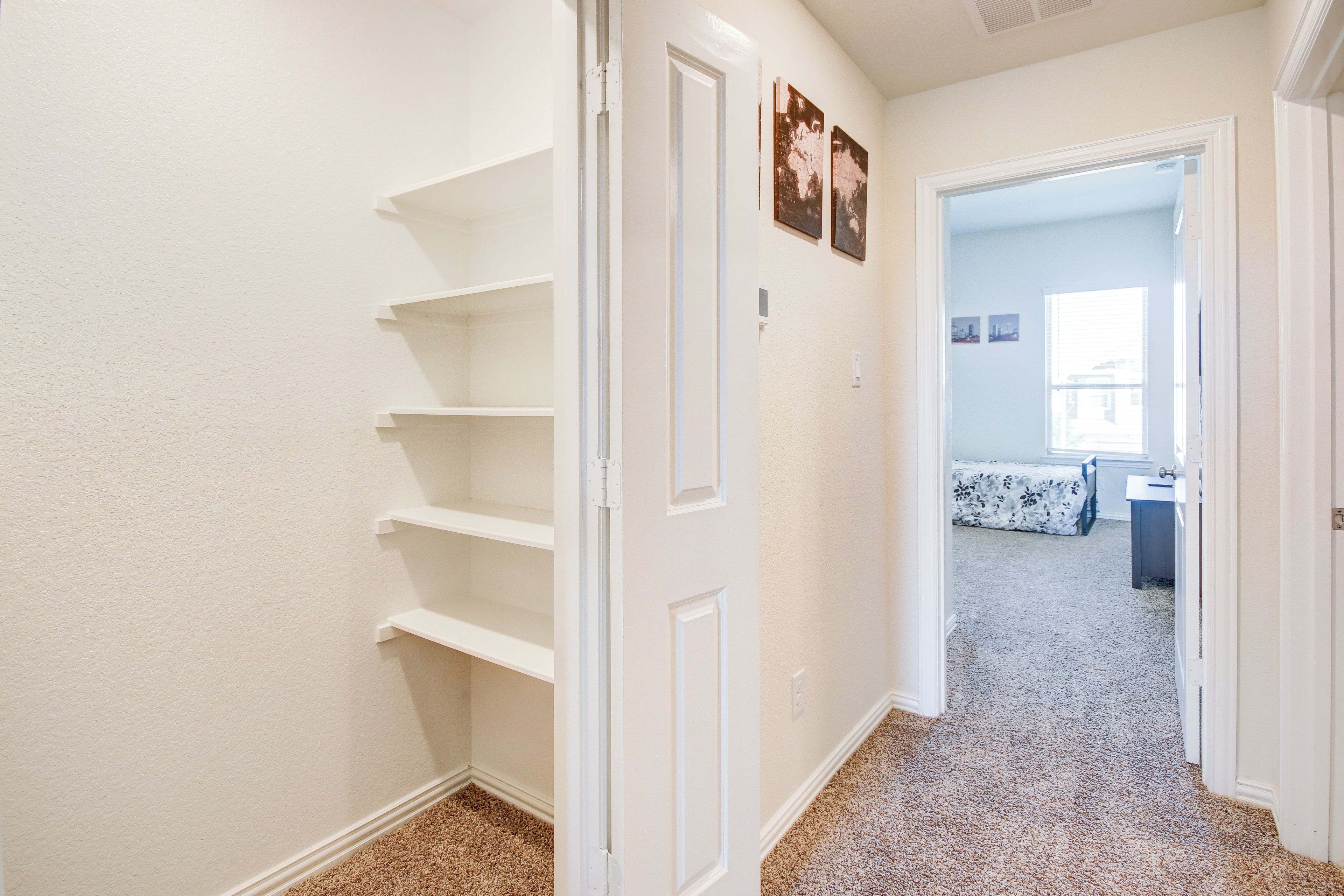 Un passadís amb una porta blanca que dona a una habitació amb un llit i una finestra.