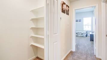 Un passadís amb una porta blanca que dona a una habitació amb un llit i una finestra.