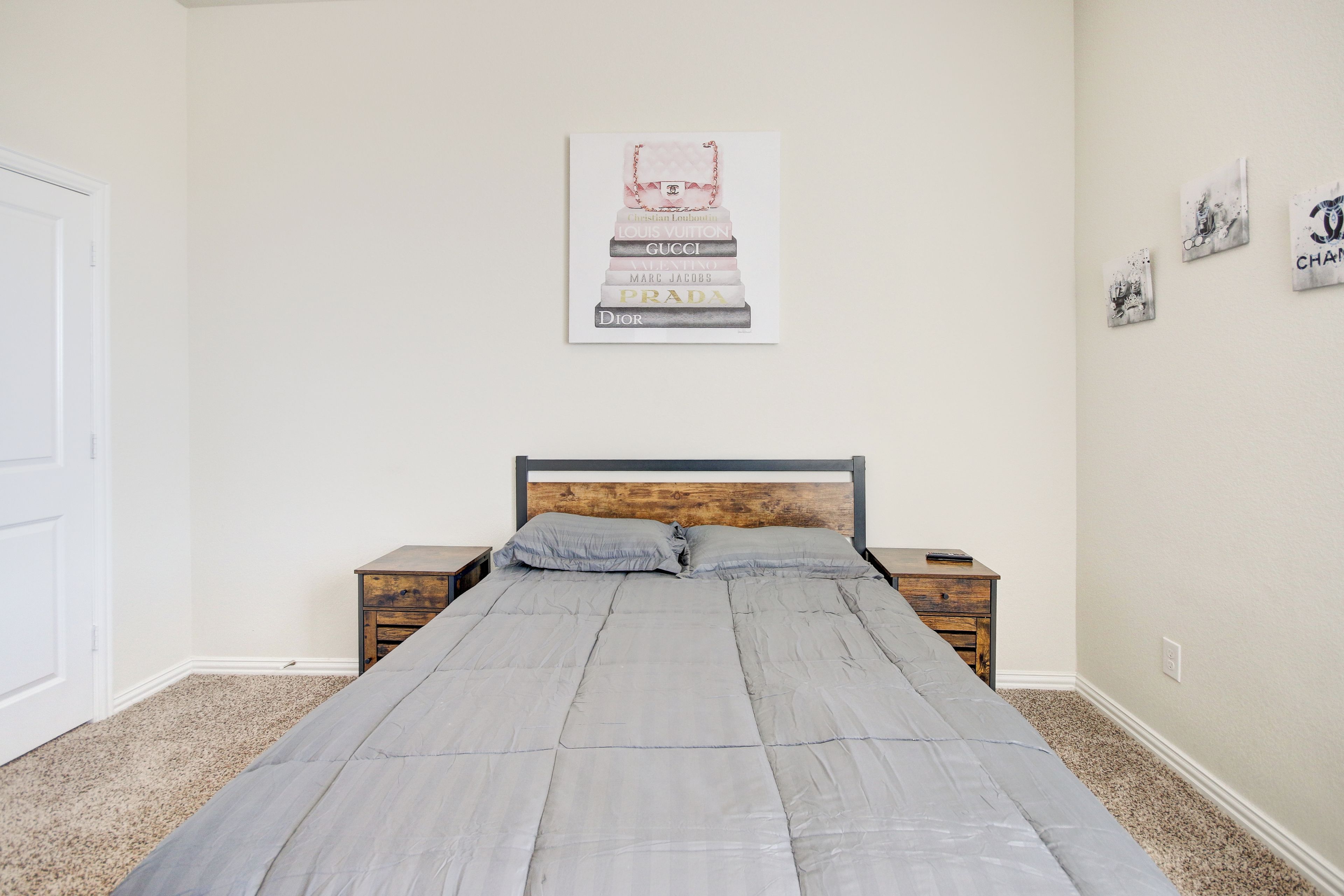A bedroom with a bed, two nightstands, a wooden headboard, and a wall with a framed poster.