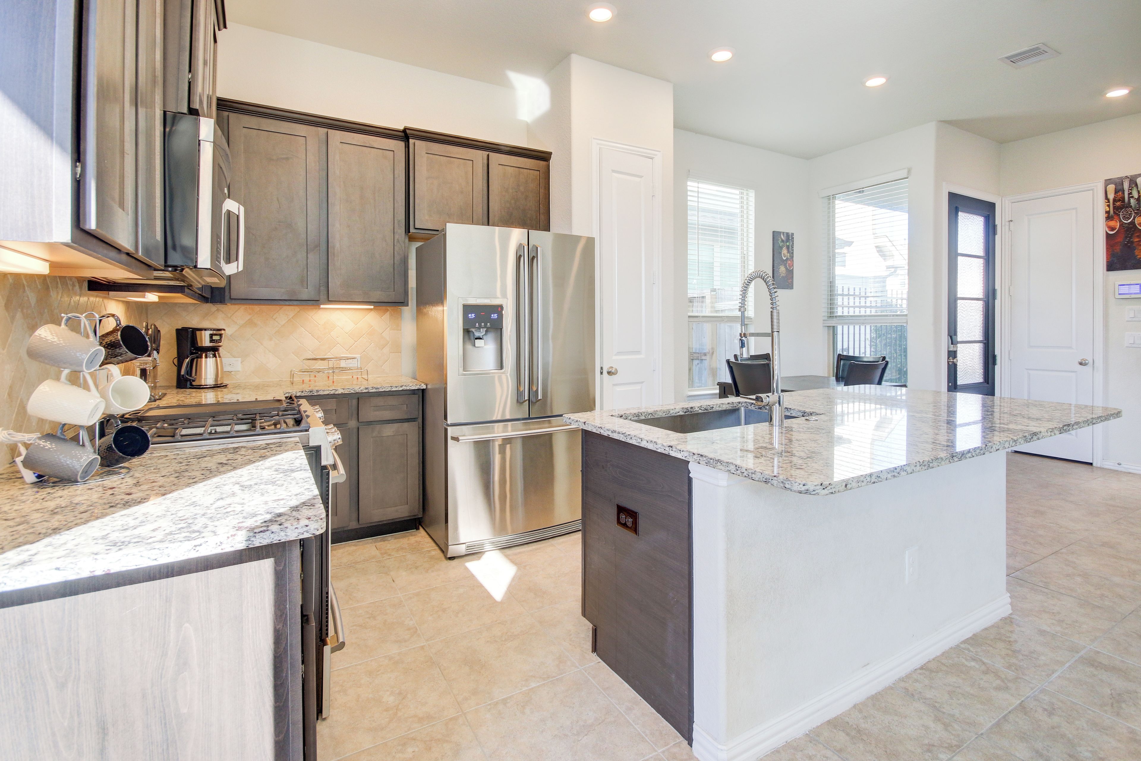 A modern kitchen with stainless steel appliances, a granite countertop, and a large island.