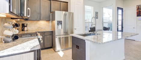 A modern kitchen with stainless steel appliances, a granite countertop, and a large island.
