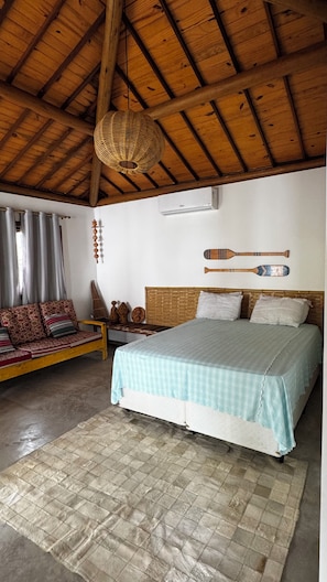 A room with a bed, a sofa, a woven ceiling light, and a wall-mounted air conditioner. - New Listing (Japaratinga)