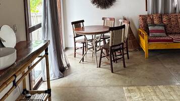 A rustic interior with a wooden ceiling, a round dining table with chairs, a sofa, and a wall-mounted decorative item.
