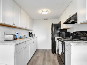 Eine moderne Küche mit weißen Schränken, einem schwarzen Kühlschrank, einer Mikrowelle, einem Herd und einem Toaster.
