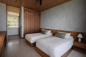 A hotel room with two beds, a wooden headboard, a nightstand, and a window with bars. - NEW 6BR Contemporary Villa Near Santa Teresa • Ocean Views • Saltwater Pool (Santa Teresa)