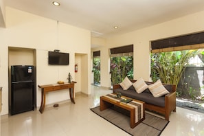A living room with a sofa, coffee table, TV, and a refrigerator. - Kadiga Villas - 2 BR pool Villa (Bali)