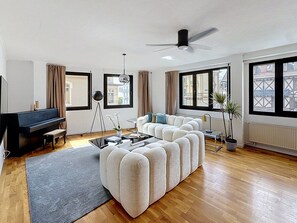 Una sala de estar moderna con un piano, sofá modular y ventanas amplias.