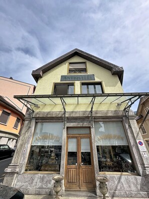 A building with a sign reading 'ANTIQUE' and a large wooden door. - Mercury · Mercury House 110 m² | Private parking | Train station 500 m away (Montreux)