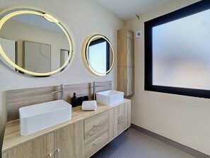 Un baño moderno con dos lavamanos, un espejo y una ventana.