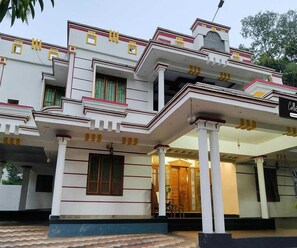 A two-story building with a balcony and a covered entrance. - Classic Balaramapuram White Castle (Neyyattinkara)