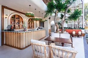 A bar area with a counter, wicker chairs, a table, and a tree. - The Arca Villa - 2 BR Pool Villa (Bali)