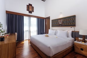 A hotel room with a large bed, a wooden desk, a nightstand, and a wall-mounted artwork. - The Arca Villa - 2 BR Pool Villa (Bali)