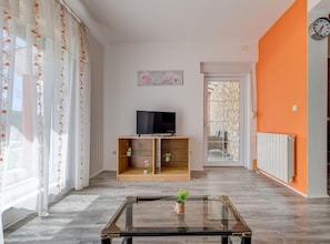 A living room with a glass coffee table, a TV on a wooden stand, and a door leading to a balcony. - Beautiful Rustic Relax Villa (Dugopolje)