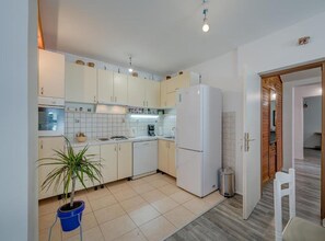 A compact kitchen with white cabinets, a built-in oven, a refrigerator, and a potted plant. - Beautiful Rustic Relax Villa (Dugopolje)