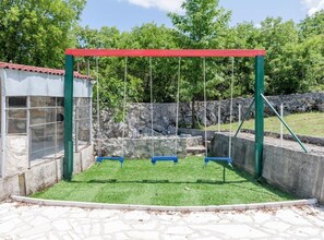 A playground with a swing set and a fenced enclosure. - Beautiful Rustic Relax Villa (Dugopolje)
