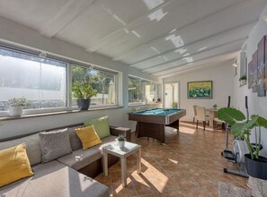 A sunlit room with a pool table, a sofa with cushions, a dining area, and large windows. - Two Bedroom Apartment with Pool View (Vodnjan)