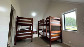 Une chambre avec deux lits superposés, une fenêtre donnant sur un paysage agréable et une porte menant à une autre pièce.