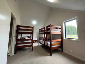Una habitació amb dos llits superposats, una finestra amb vista i una porta que dona a una altra habitació.