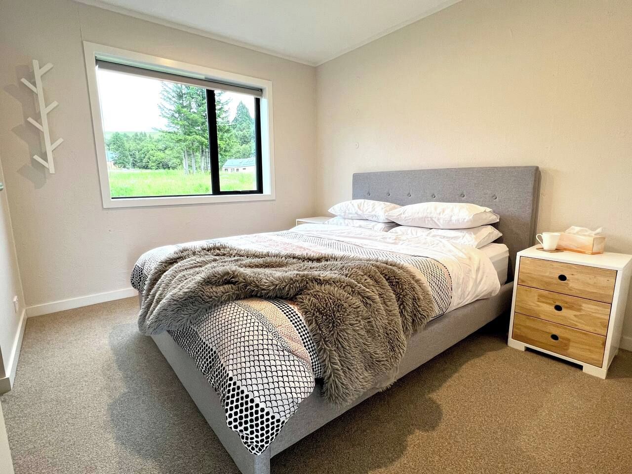 A bedroom with a bed, a nightstand, a window, and a door.