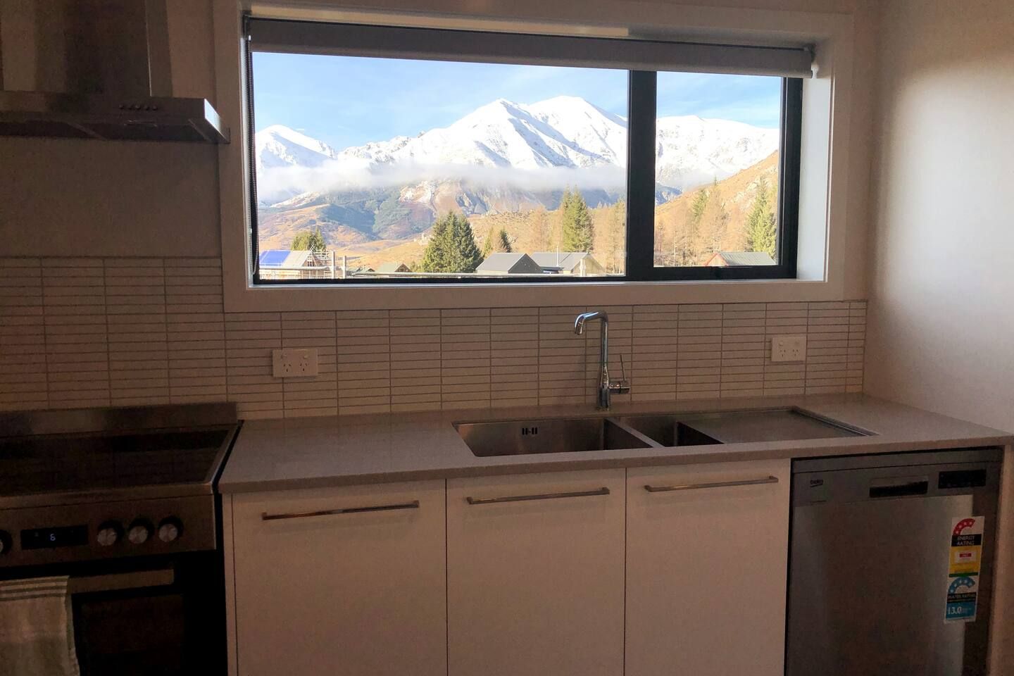 A kitchen with a window view of snow-capped mountains.