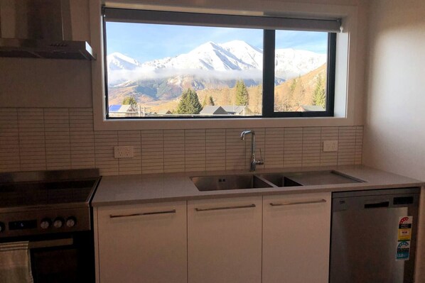 A kitchen with a window view of snow-capped mountains.