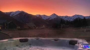 Un bain à remous avec vue sur des montagnes enneigées au coucher du soleil.
