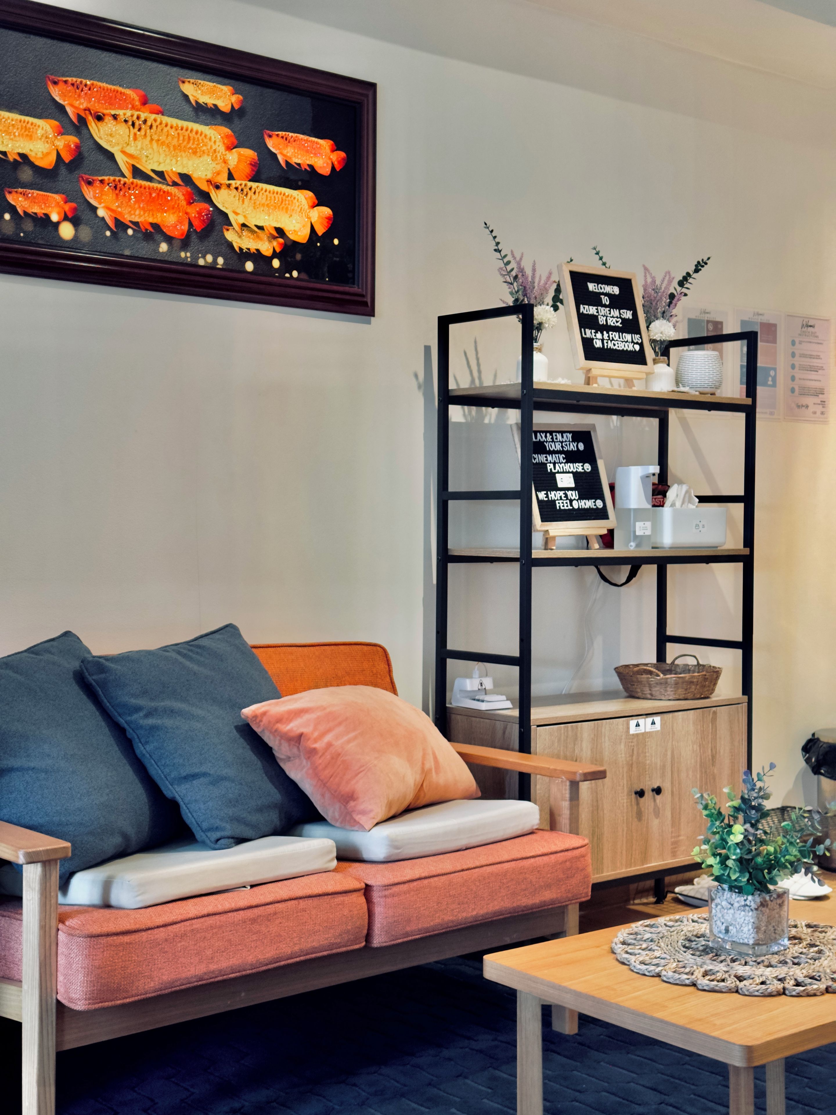 A cozy seating area with a sofa, cushions, a coffee table, and a decorative fish painting.