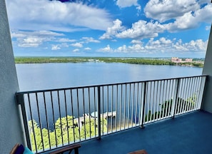 A balcony with a view of a large body of water, greenery, and distant buildings. - Balcony Lake Views | Pool, Gym, WiFi & Parking (Orlando)