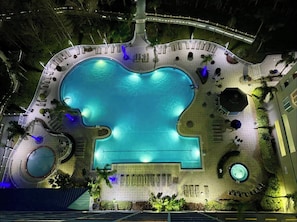An aerial view of a hotel pool area with a large central pool, surrounding lounge areas, and a small circular pool. - Balcony Lake Views | Pool, Gym, WiFi & Parking (Orlando)