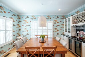 A dining area with a wooden table, chairs, a hanging light fixture, and a wall with fish decals. - Newly Renovated Annapolis Escape with Pool, Hot Tub & Sauna (Annapolis)