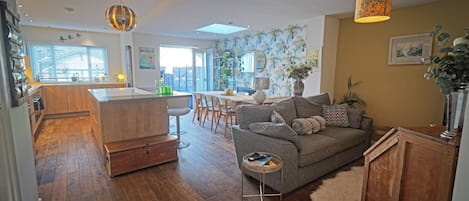 Un espacio habitable moderno con cocina, comedor y una zona de estar acogedora con sofá y mesita auxiliar.