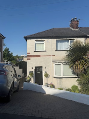 A two-story residential building with a brick facade, a chimney, and a car parked in the driveway. - Beautiful House 5 Mins Walk Into Ulverston (Ulverston)