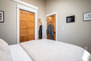 Quarto com uma cama de casal, duas portas de madeira e um quadro na parede.
