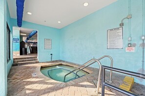 Une petite piscine intérieure avec un mur bleu, un panneau d’avertissement et un panneau indiquant les règles de la piscine.