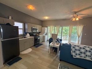 A compact kitchen with modern appliances, a dining area with a blue sofa, and a balcony with curtains. - Luxurious Beach Front Villa Pool-Gym-AC Sleeps 5! (Turtle Bay)
