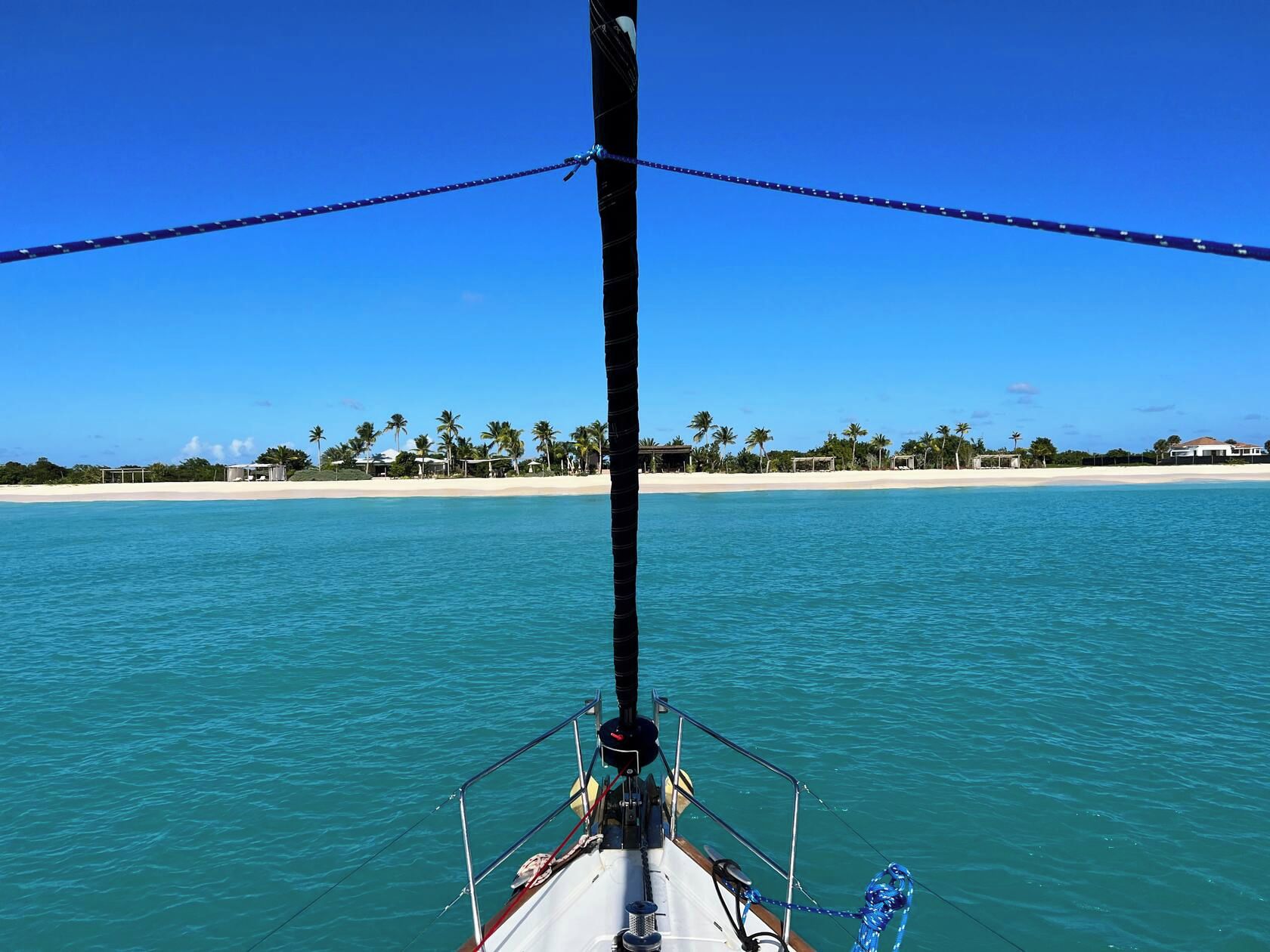 A boat with a view of a beach and palm trees in the distance.