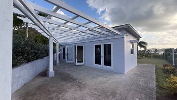 A covered outdoor area with a concrete floor, white walls, and a glass door entrance.