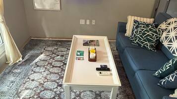A living room with a sofa, a coffee table, a television, and a patterned rug.